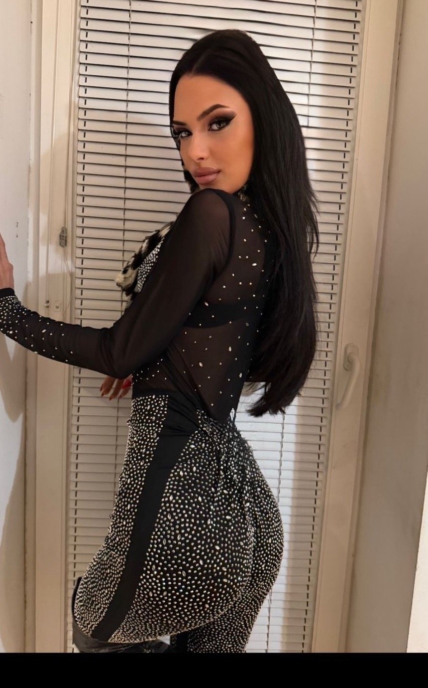 Lana Bajc posing in a fitted embellished black dress.